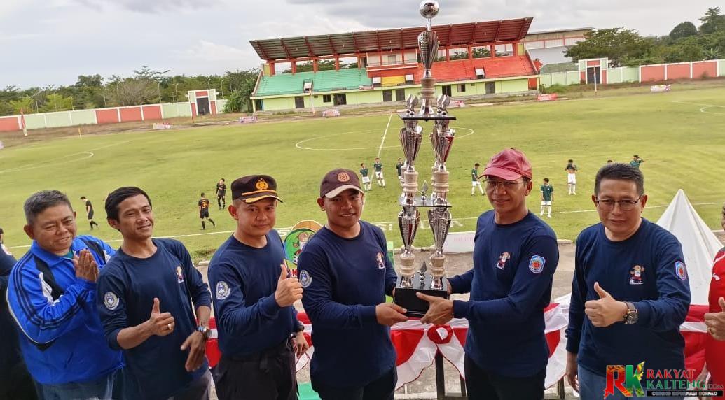 Bupati Mura Drs Perdie M Yoseph, MA saat menyerahkan piala bergilir Open Turnamen Piala Askab PSSI Mura kepada Ketua Panitia Reno, S.Kom., M.I.Kom.